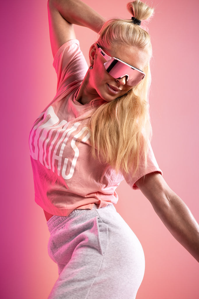 Woman wearing sunglasses for bike riding with pink frame and lens